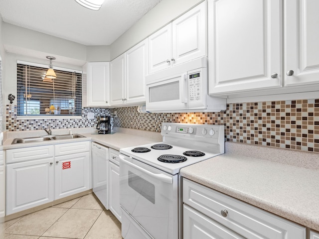 kitchen featuring white appliances, white cabinets, sink, light tile patterned floors, and decorative light fixtures