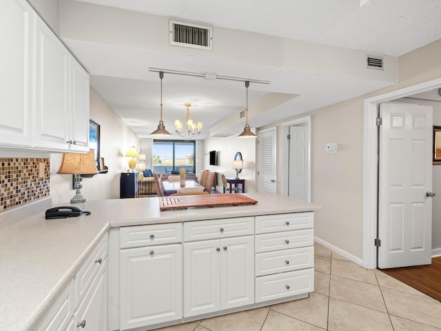 kitchen featuring tasteful backsplash, light tile patterned flooring, a notable chandelier, a textured ceiling, and white cabinets