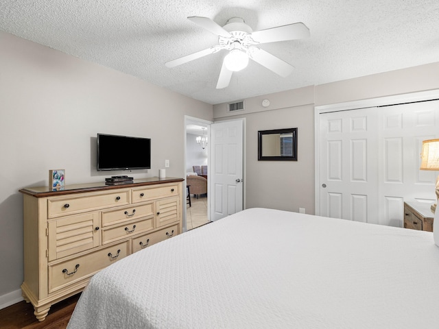 bedroom with a textured ceiling, a closet, ceiling fan, and dark wood-type flooring