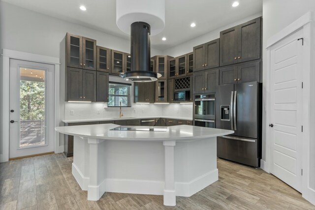 kitchen with tasteful backsplash, light hardwood / wood-style flooring, a kitchen island, island exhaust hood, and black appliances