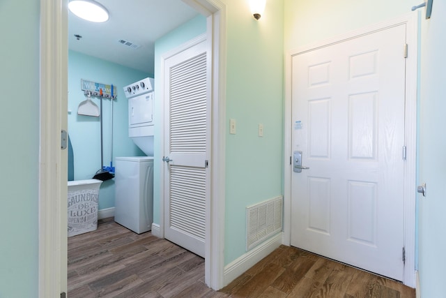 laundry room with hardwood / wood-style floors and stacked washer and clothes dryer