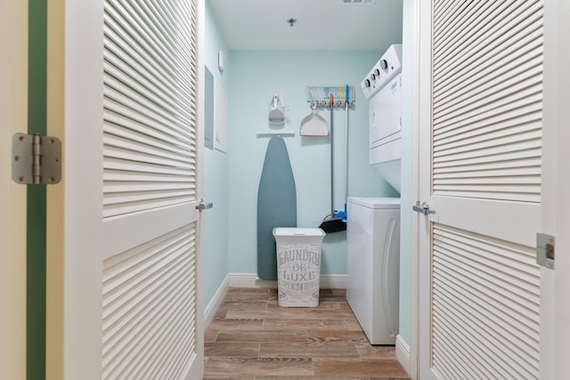 laundry area with light wood-type flooring and stacked washer and dryer