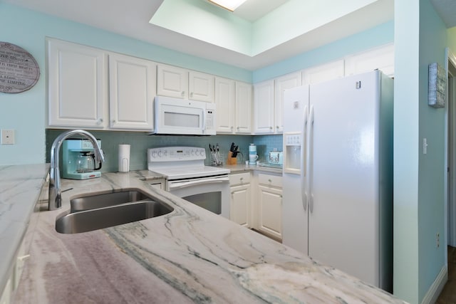 kitchen with light stone countertops, white appliances, white cabinetry, and sink