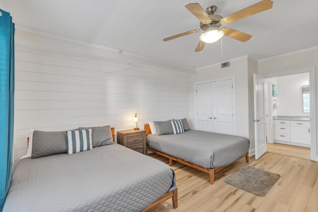 bedroom featuring light wood-type flooring, ornamental molding, ceiling fan, wooden walls, and a closet