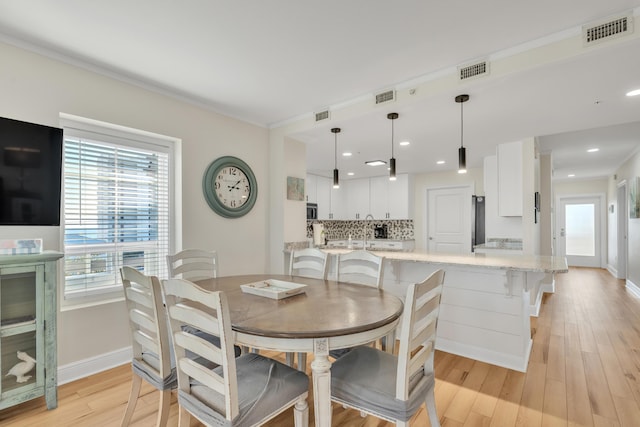 dining area featuring a wealth of natural light, sink, and light wood-type flooring