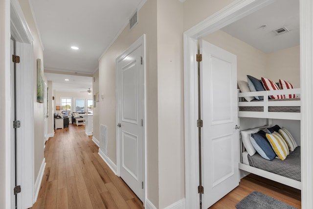 hall with crown molding and light hardwood / wood-style flooring