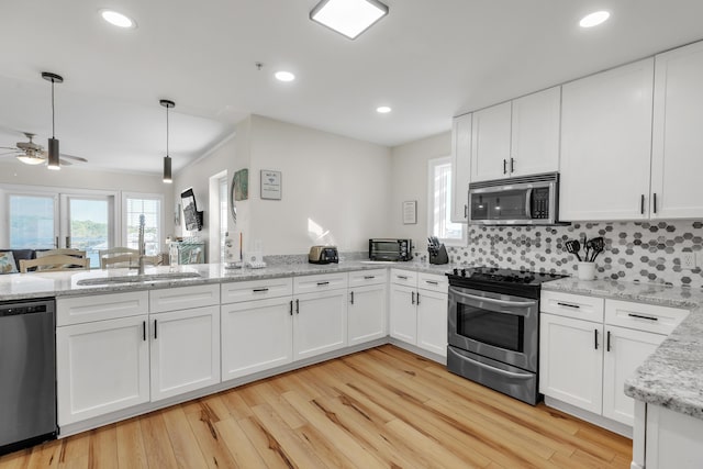 kitchen featuring decorative light fixtures, stainless steel appliances, white cabinetry, and sink