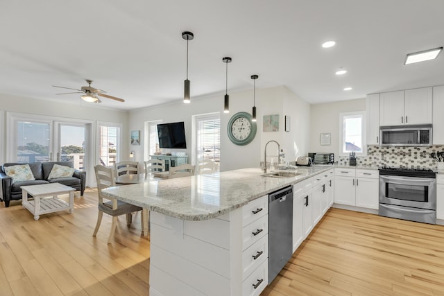 kitchen featuring kitchen peninsula, stainless steel appliances, white cabinetry, and hanging light fixtures