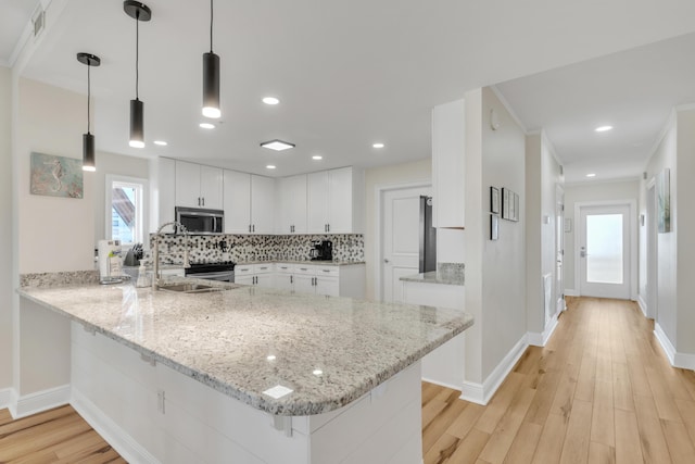 kitchen featuring kitchen peninsula, pendant lighting, white cabinetry, and light stone counters