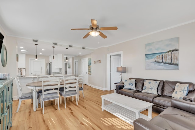 living room featuring light hardwood / wood-style floors, ceiling fan, and crown molding