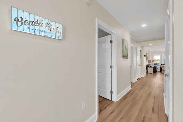 hallway with light hardwood / wood-style flooring and ornamental molding