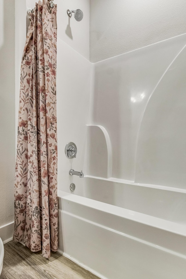 bathroom with hardwood / wood-style floors and shower / tub combo with curtain