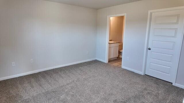 unfurnished bedroom with ensuite bathroom and light colored carpet