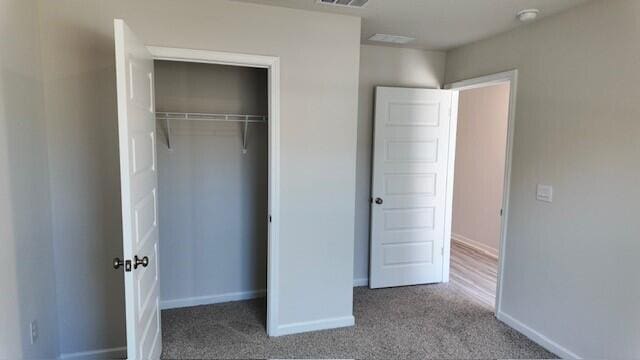 unfurnished bedroom featuring light colored carpet and a closet