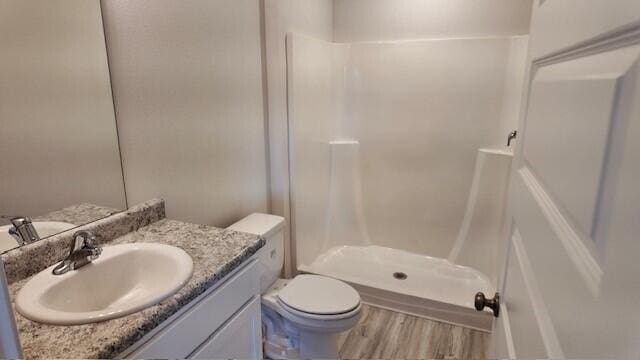 bathroom featuring a shower, vanity, hardwood / wood-style flooring, and toilet