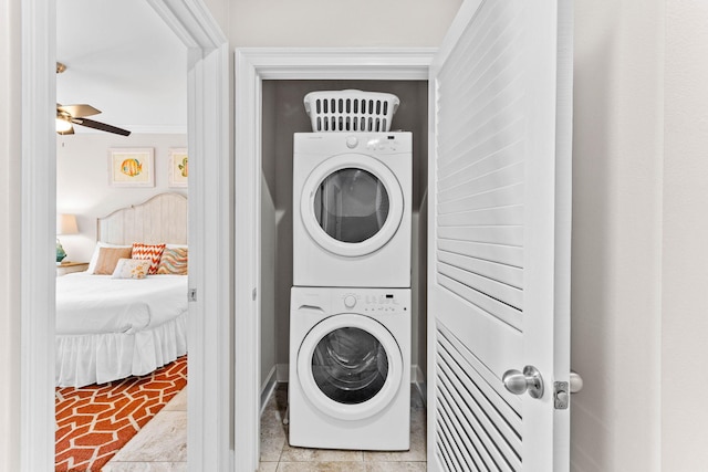 laundry area featuring ceiling fan, light tile patterned flooring, ornamental molding, and stacked washer and dryer