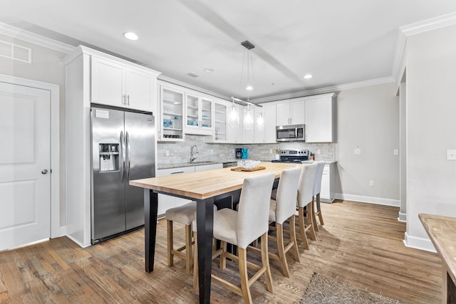 kitchen featuring white cabinetry, sink, dark wood-type flooring, stainless steel appliances, and pendant lighting