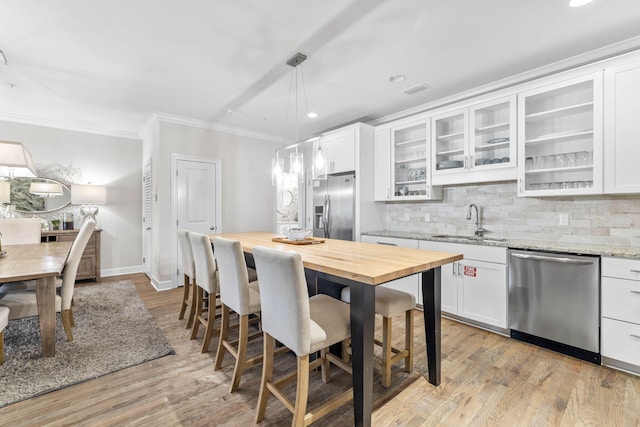 kitchen with appliances with stainless steel finishes, light wood-type flooring, white cabinetry, and light stone counters