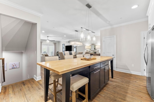 kitchen featuring stainless steel fridge, light wood-type flooring, and crown molding