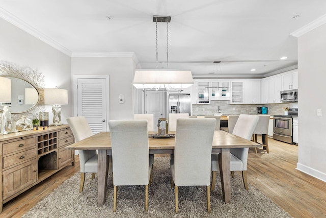 dining area with light hardwood / wood-style floors and ornamental molding