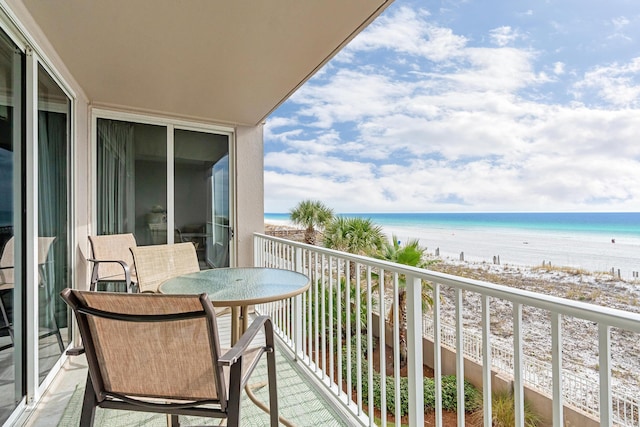 balcony with a water view and a view of the beach