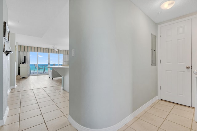 hallway featuring a textured ceiling, electric panel, and light tile patterned flooring