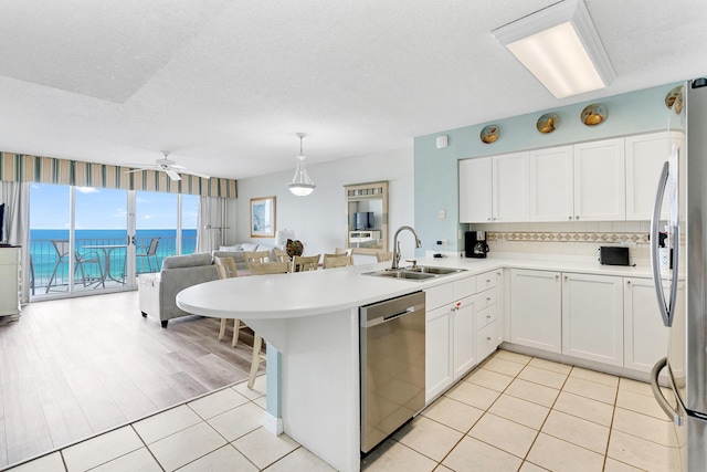 kitchen with kitchen peninsula, ceiling fan, sink, and stainless steel appliances