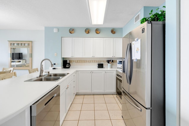 kitchen with sink, light tile patterned floors, a textured ceiling, white cabinetry, and stainless steel appliances