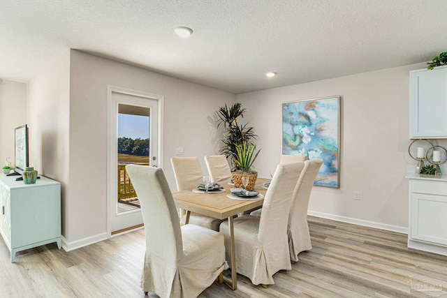 dining space with a textured ceiling and light hardwood / wood-style flooring