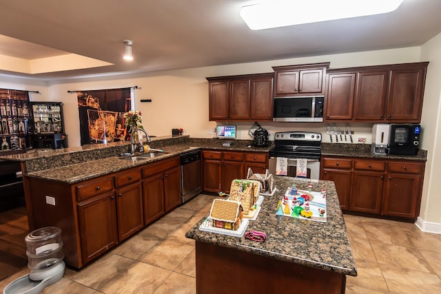 kitchen with kitchen peninsula, stainless steel appliances, dark stone counters, and sink