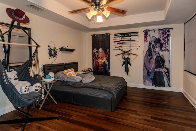 bedroom featuring a raised ceiling, ceiling fan, and dark hardwood / wood-style flooring