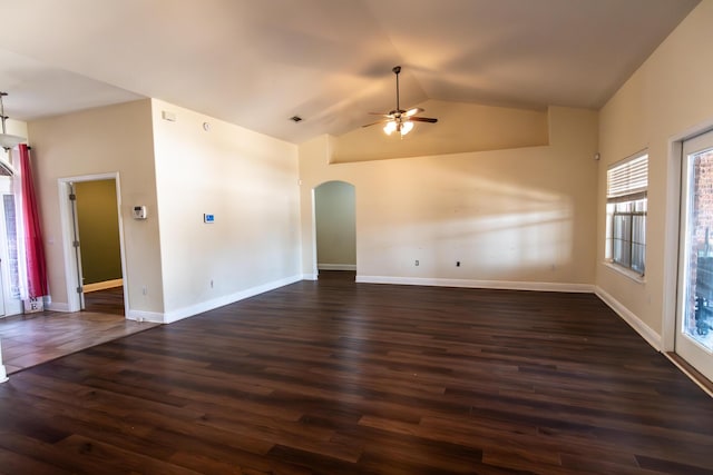 spare room featuring baseboards, arched walkways, a ceiling fan, lofted ceiling, and dark wood-type flooring