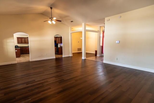 unfurnished living room with arched walkways, lofted ceiling, dark wood-type flooring, visible vents, and a ceiling fan