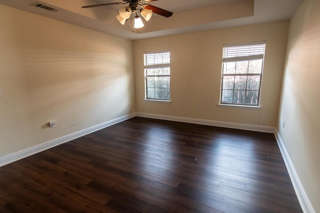 spare room with dark wood-style floors, baseboards, visible vents, and ceiling fan