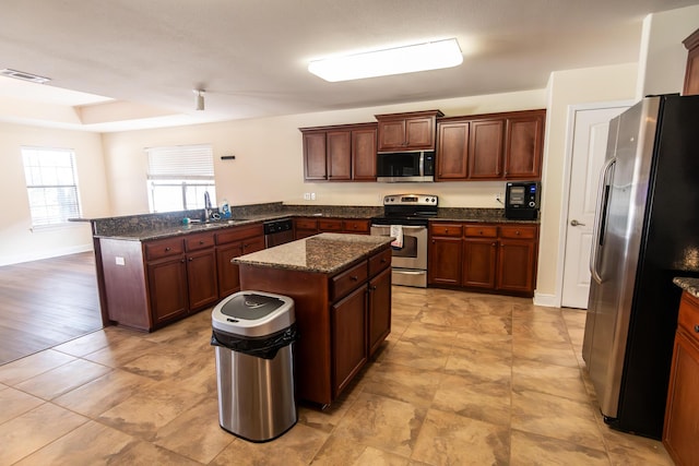 kitchen with stainless steel appliances, a peninsula, a sink, visible vents, and a center island