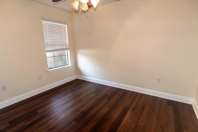 empty room with dark wood finished floors, a ceiling fan, and baseboards