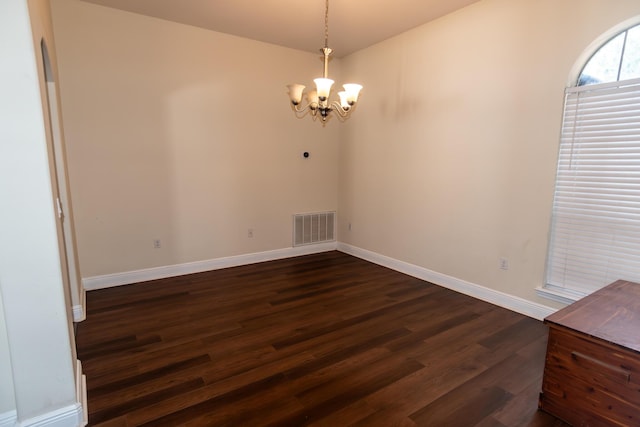 empty room with baseboards, visible vents, dark wood finished floors, and a notable chandelier