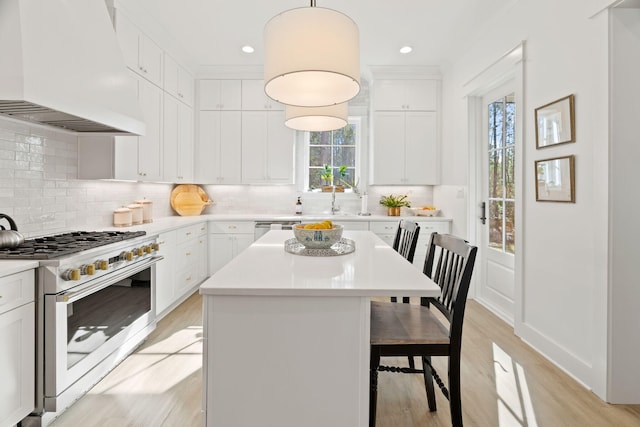 kitchen featuring premium range hood, decorative light fixtures, a kitchen bar, designer range, and a kitchen island