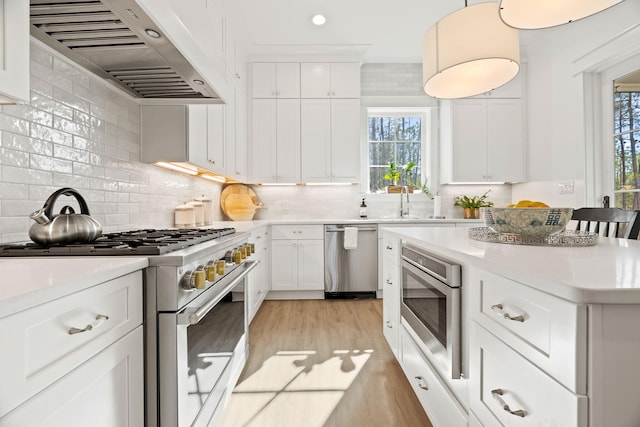 kitchen featuring white cabinets, extractor fan, appliances with stainless steel finishes, and tasteful backsplash