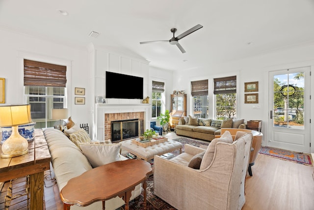 living room featuring light hardwood / wood-style floors, a brick fireplace, and ceiling fan