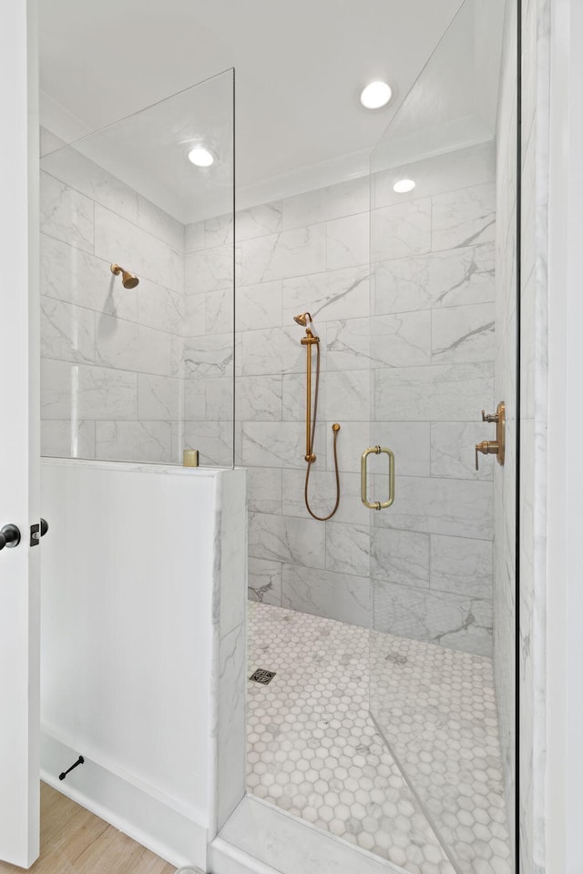 bathroom with hardwood / wood-style floors and a shower with shower door