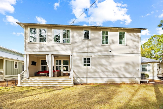 rear view of property featuring a lawn and covered porch