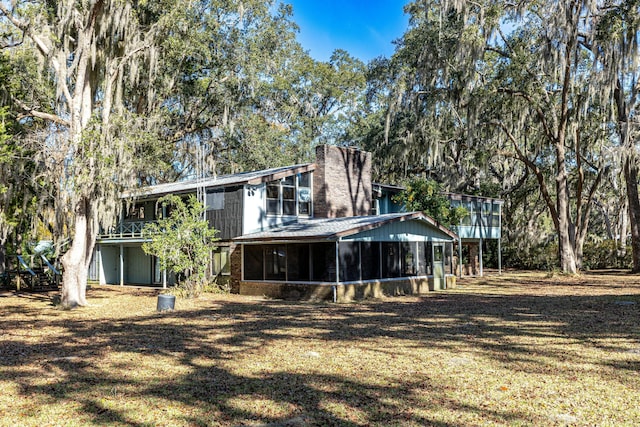 rear view of house with a yard and a sunroom