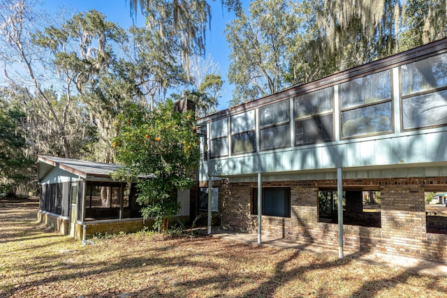 back of house with a sunroom and a lawn