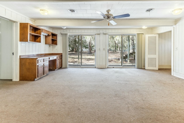 unfurnished living room with ceiling fan, light colored carpet, and a wealth of natural light