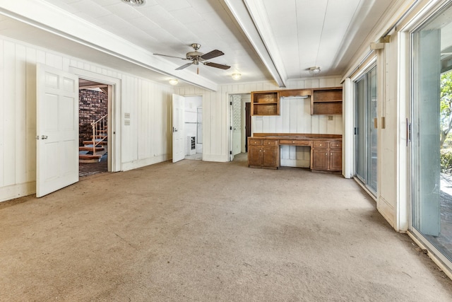 unfurnished living room featuring beamed ceiling, light colored carpet, and ceiling fan