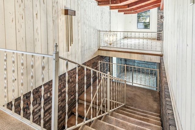 staircase featuring wooden walls and a chandelier