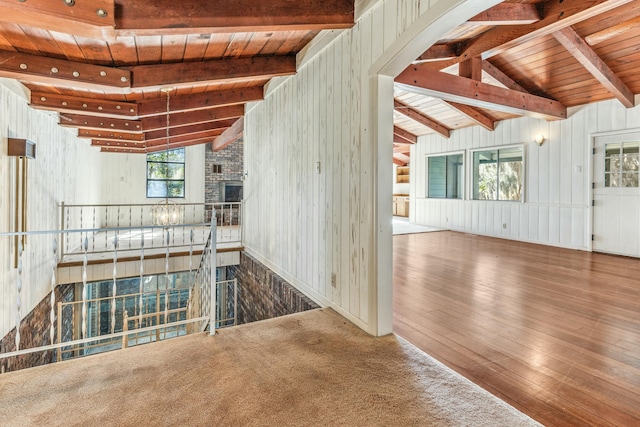 unfurnished living room with lofted ceiling with beams, wood-type flooring, and wood walls