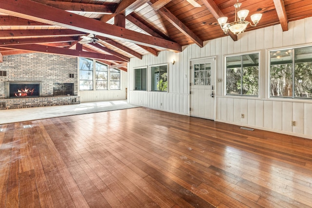 unfurnished sunroom featuring wooden ceiling, a fireplace, ceiling fan with notable chandelier, and vaulted ceiling with beams