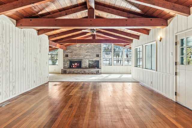 unfurnished living room featuring hardwood / wood-style flooring, a brick fireplace, and a healthy amount of sunlight